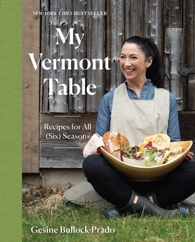 A book with woman sittig with food in a bowl on her lap in front of a barn door