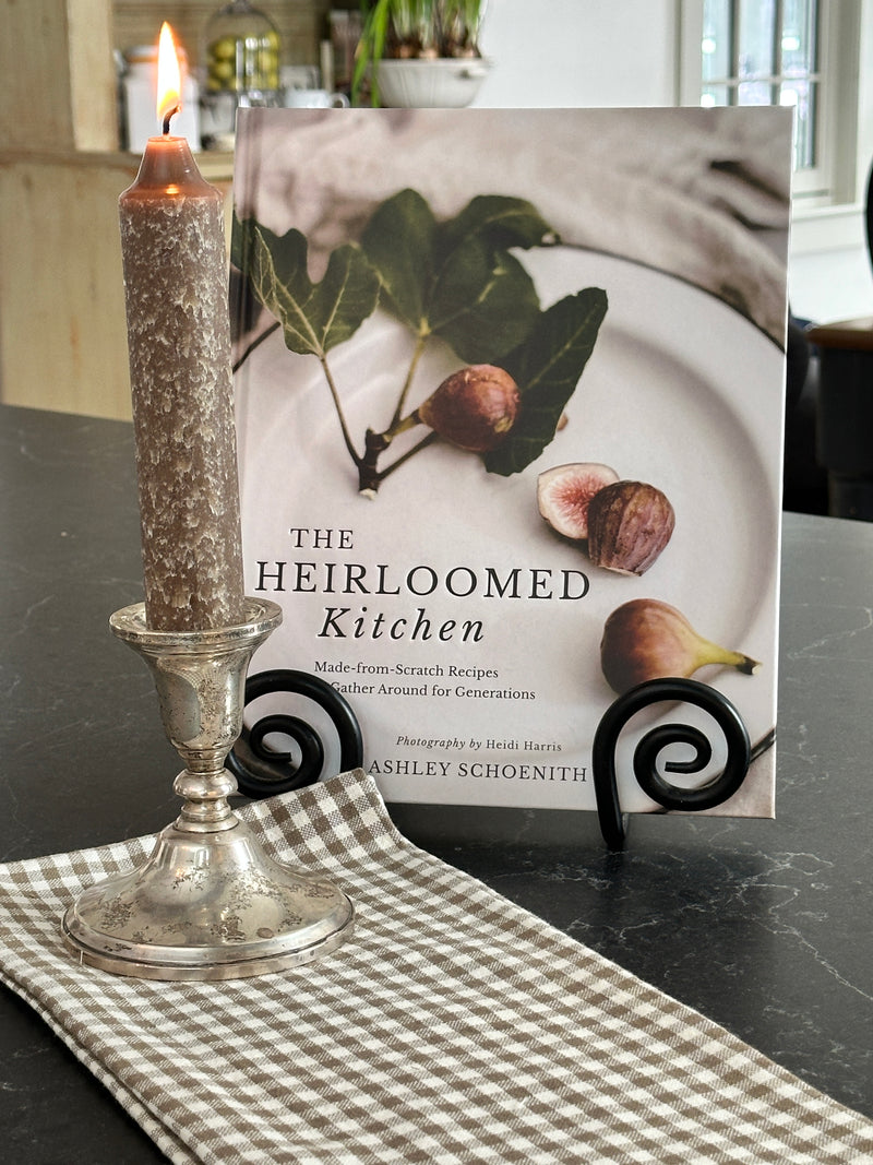Book titled 'The Heirloomed Kitchen' on a table with a decorative glass item.