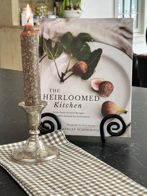 Book titled 'The Heirloomed Kitchen' on a table with a decorative glass item.