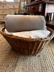 picture of a bolster pillow in a basket of vintage linens on a jute rug in New England