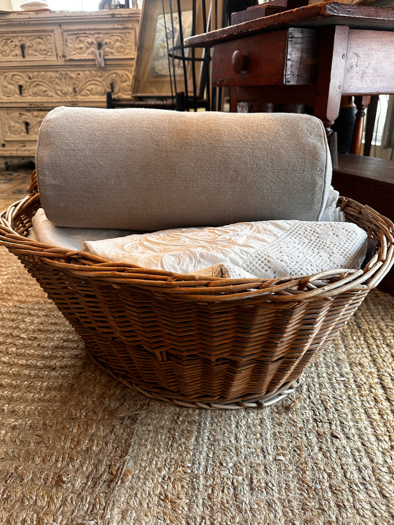 picture of a bolster pillow in a basket of vintage linens on a jute rug in New England