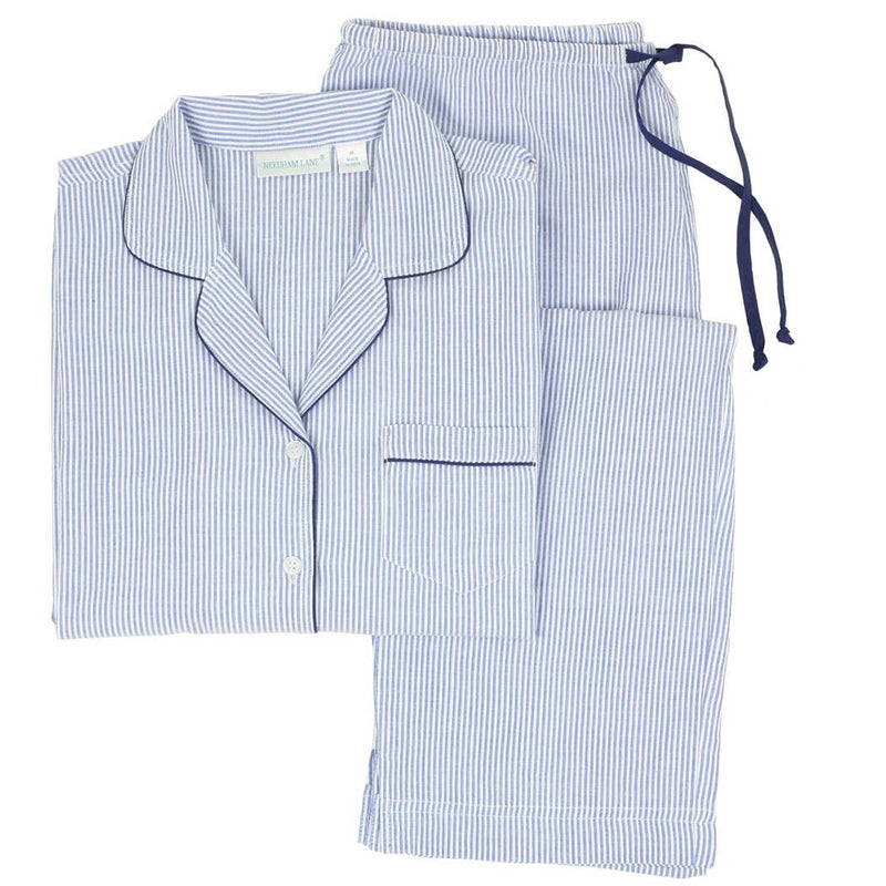 A set of long sleeve pajamas with blue and white stripes and navy piping, including a button-front top with a notched collar and side slits, and matching full-length pants with side-seam pockets and an elastic waistband with a drawstring.