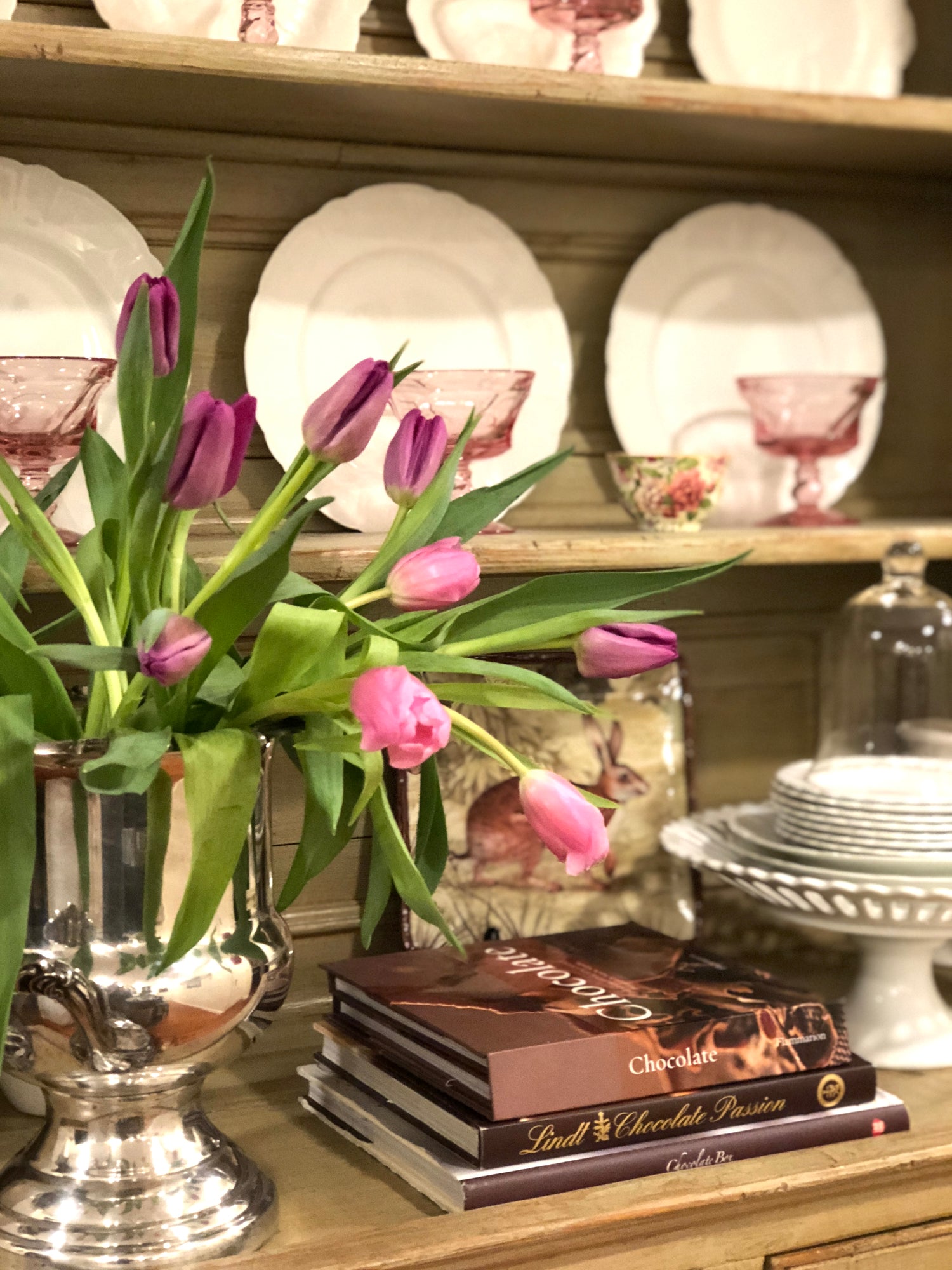 Spring tulips on open kitchen shelves in a historic New England home, styled with ironstone plates, books, and everyday kitchen décor.